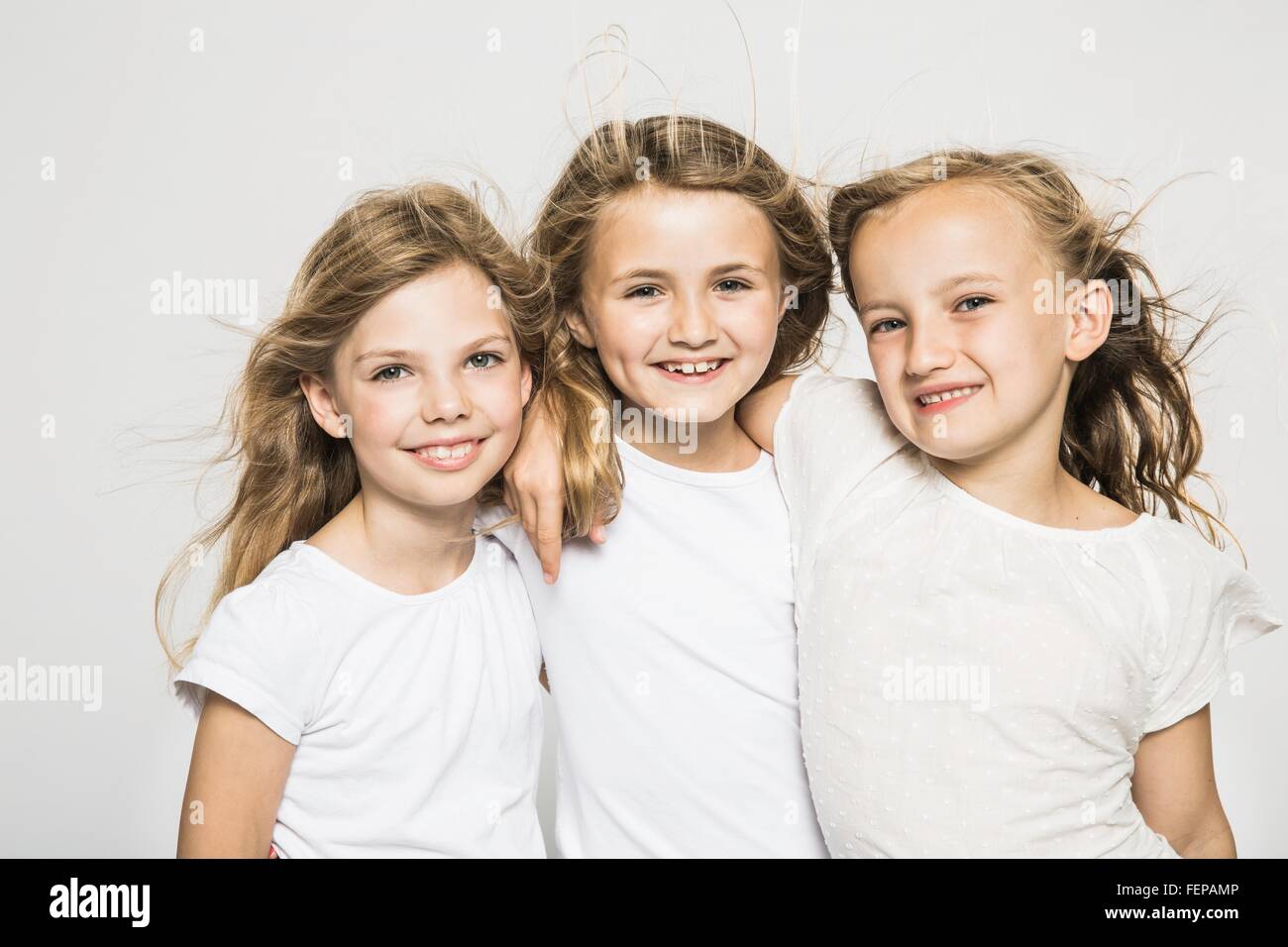 Studio portrait of three girls with long blond flyaway hair Stock Photo