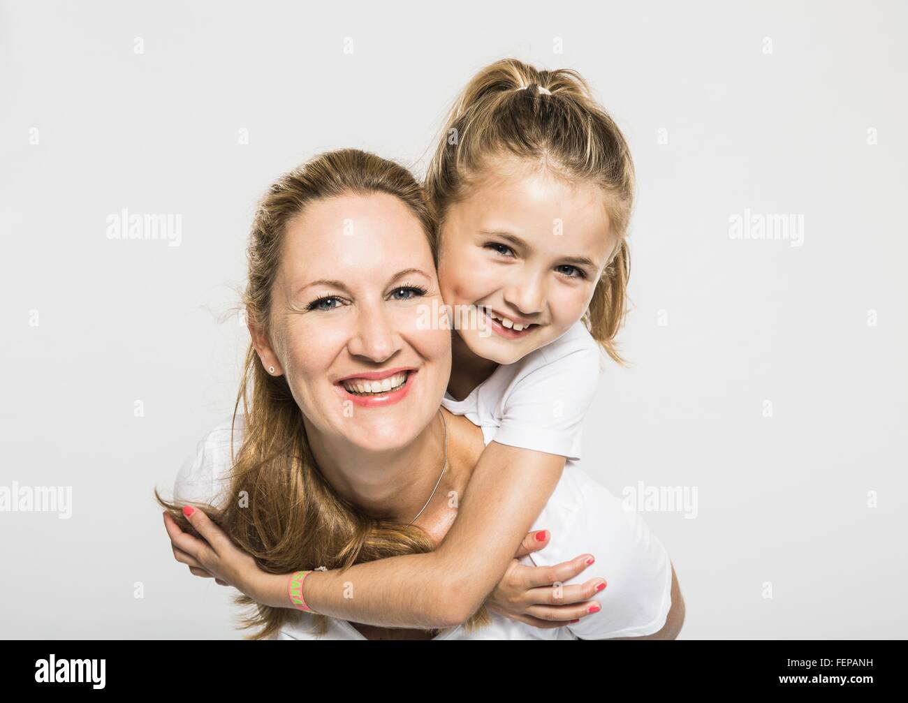 Studio portrait of happy girl getting piggyback from mother Stock Photo