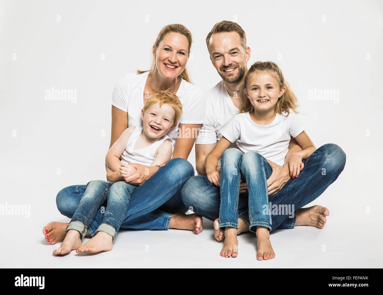 Studio portrait of boy and girl with mature parents sitting on floor Stock Photo