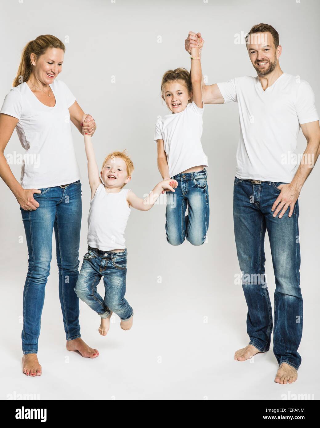 Studio portrait of mature parents lifting up son and daughter by the hands Stock Photo