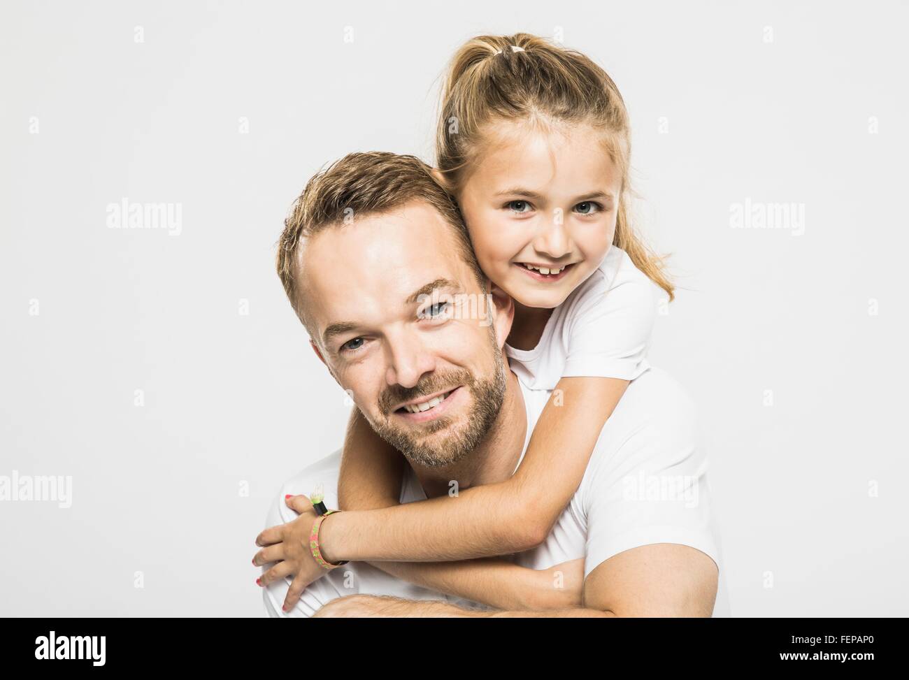 Studio portrait of girl getting piggyback from father Stock Photo