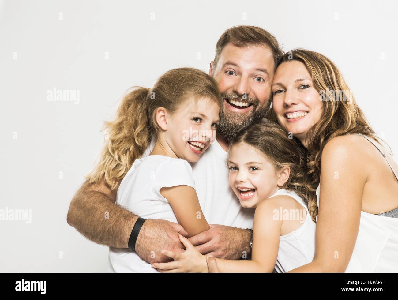 Studio portrait of two sisters and parents hugging each other Stock Photo
