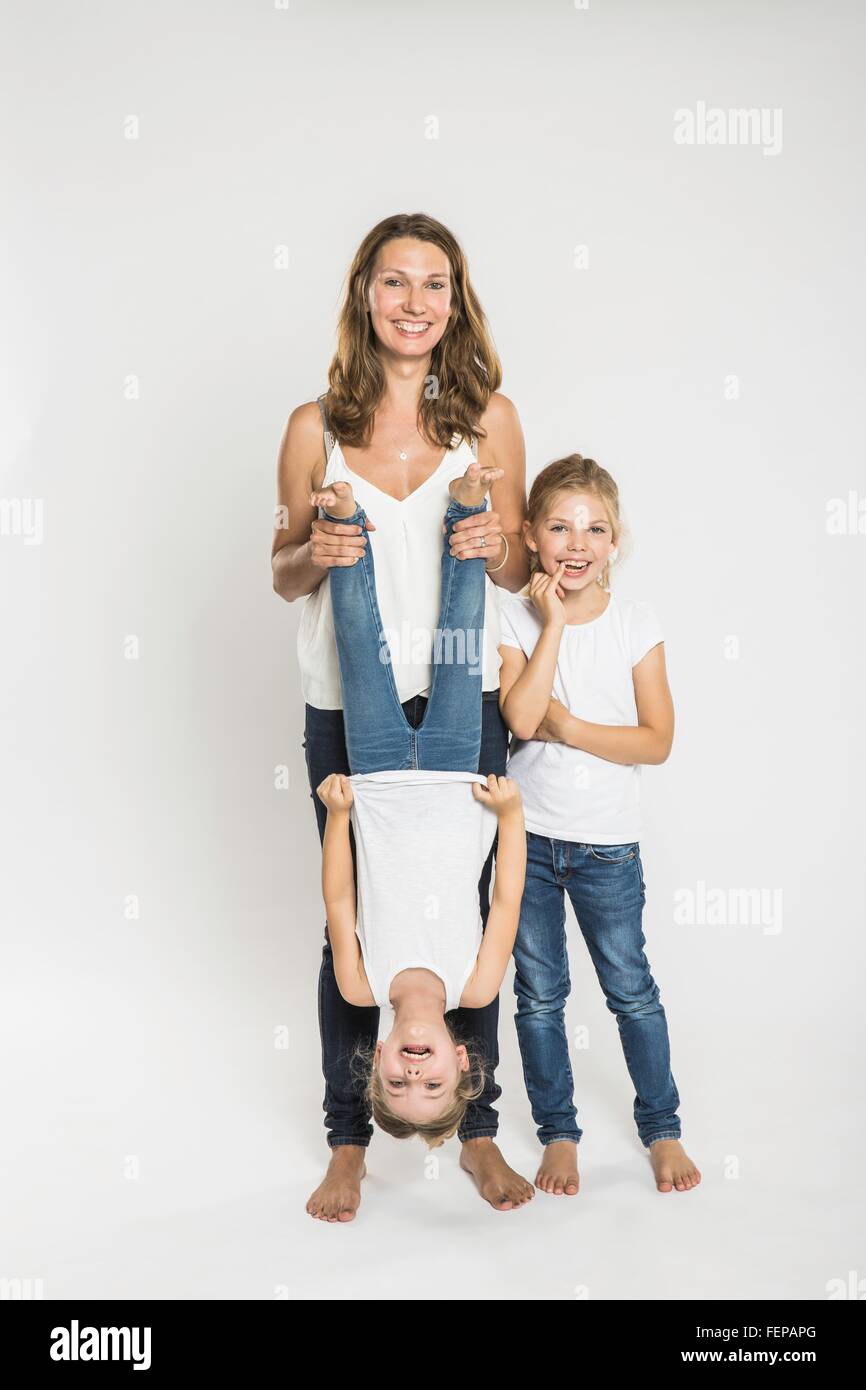 Studio portrait of mid adult woman holding one of two daughters upside down Stock Photo
