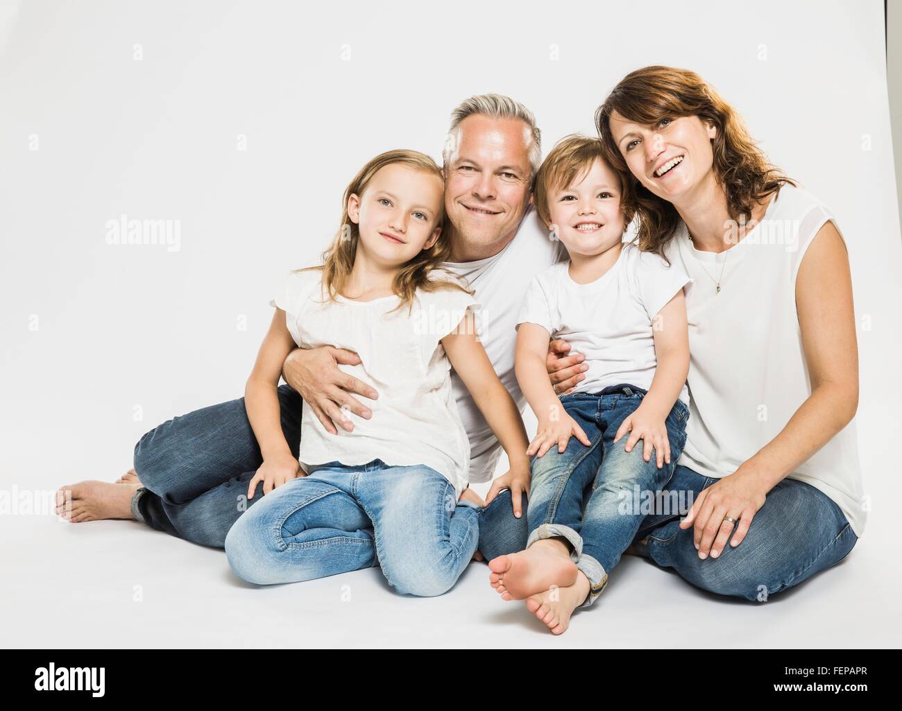 Studio portrait of parents sitting on floor with son and daughter Stock Photo