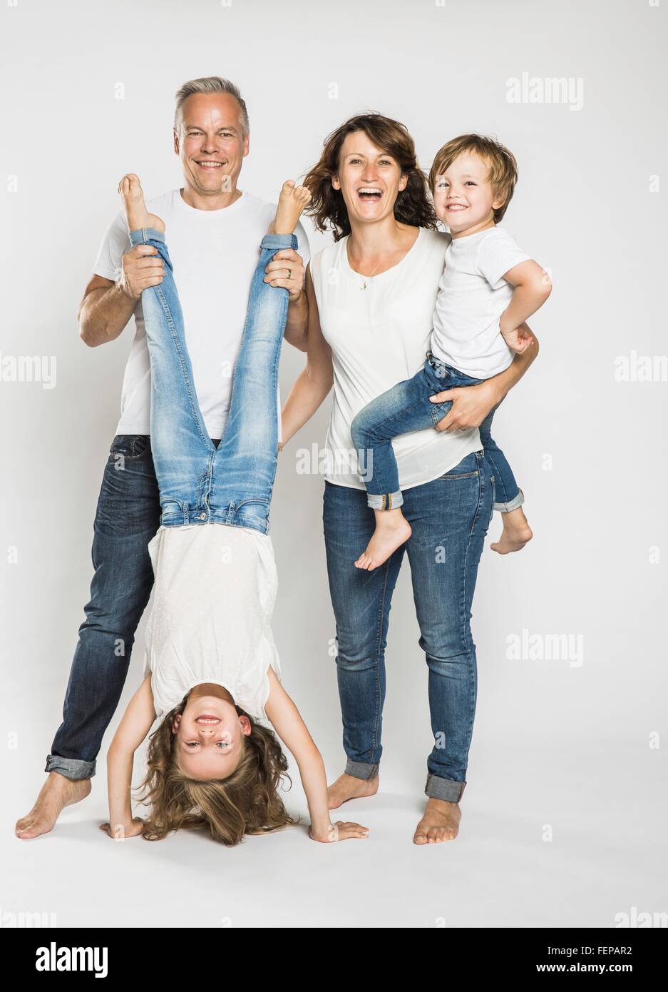 Studio portrait of man holding daughter upside down with wife and son Stock Photo