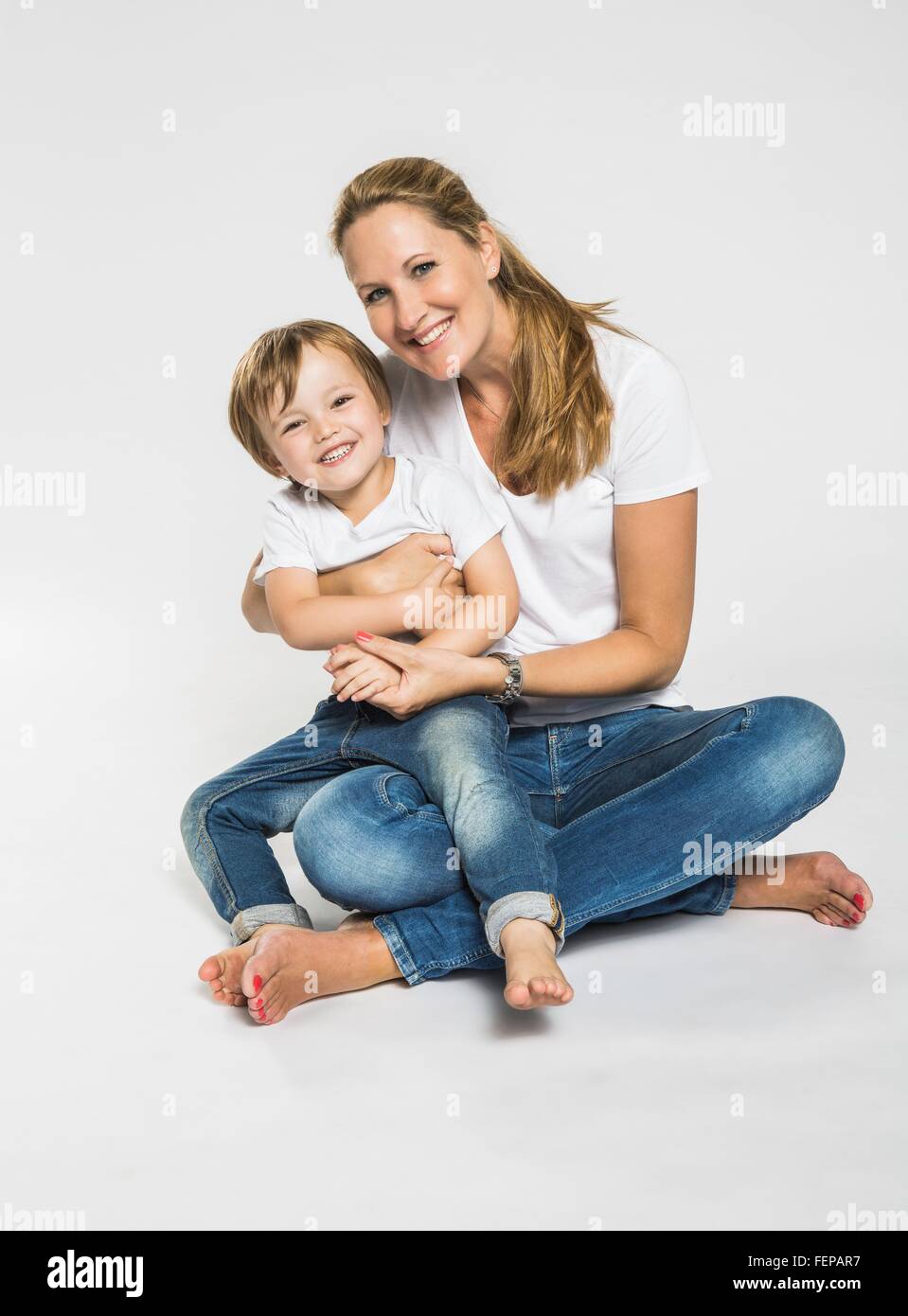 Studio portrait of mid adult woman sitting on floor with son Stock Photo