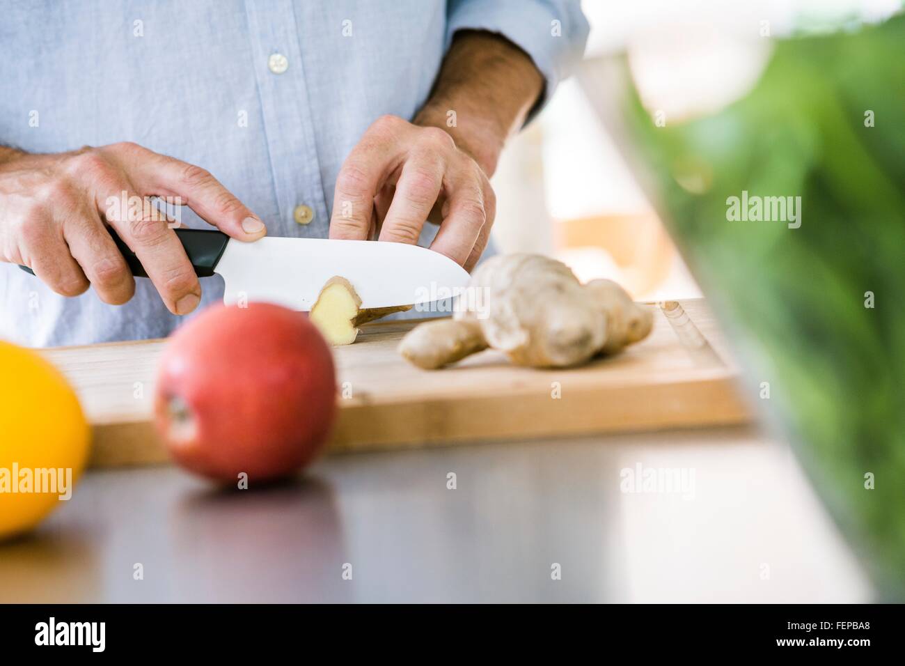 Close up of mature male hands chopping ginger Stock Photo