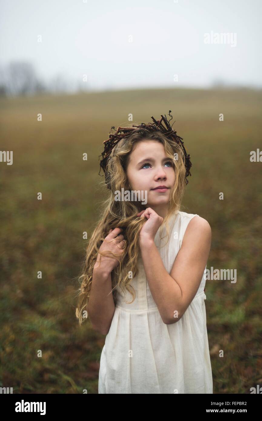 Portrait of long blond haired girl gazing up from field Stock Photo