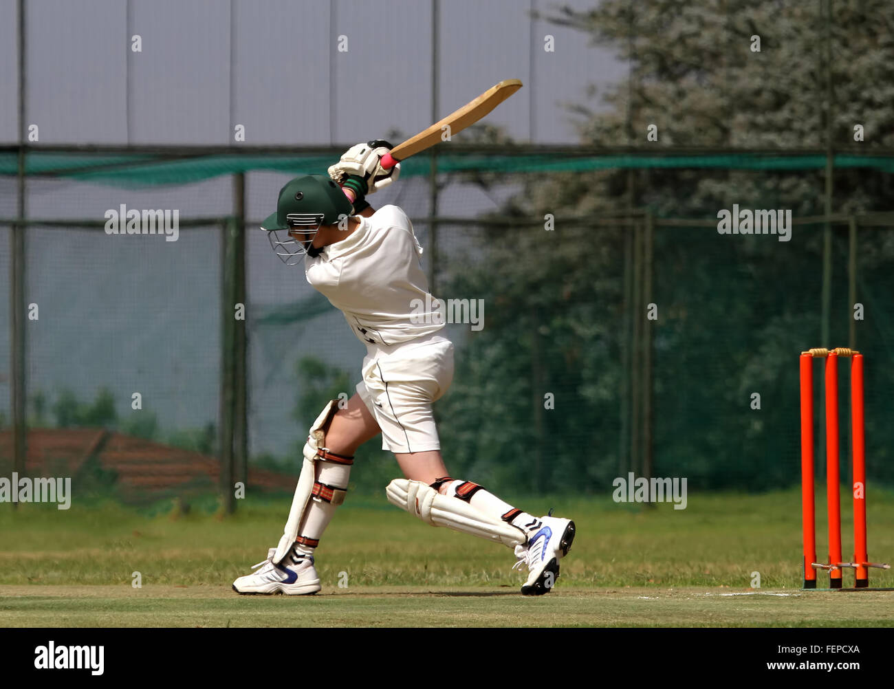 A young left hand cricket player drives the ball through the covers and ends with a beautiful follow-through Stock Photo