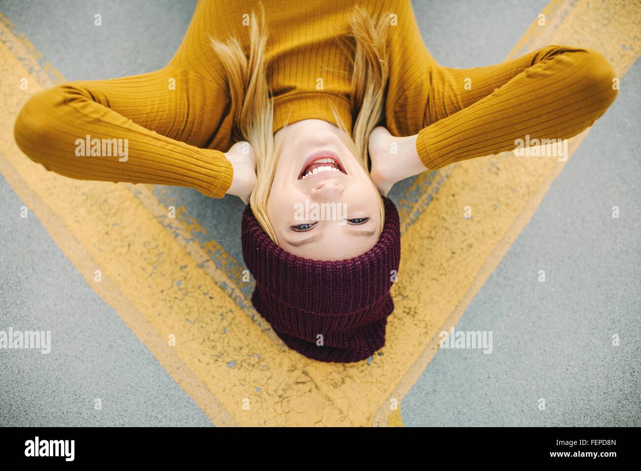Overhead portrait of young woman lying on yellow road marking Stock Photo