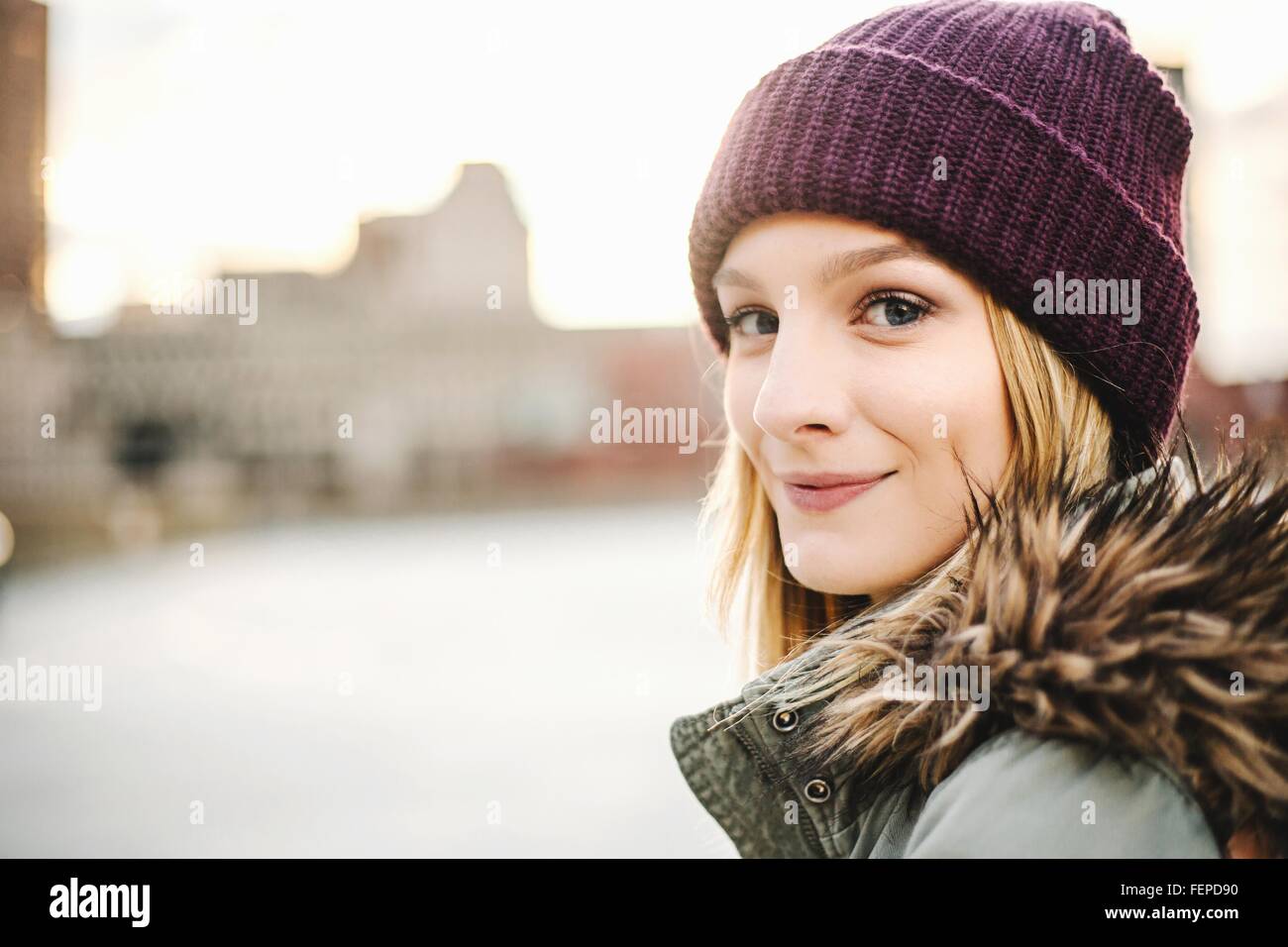 Portrait of young woman wearing knitted hat and fur hood Stock Photo