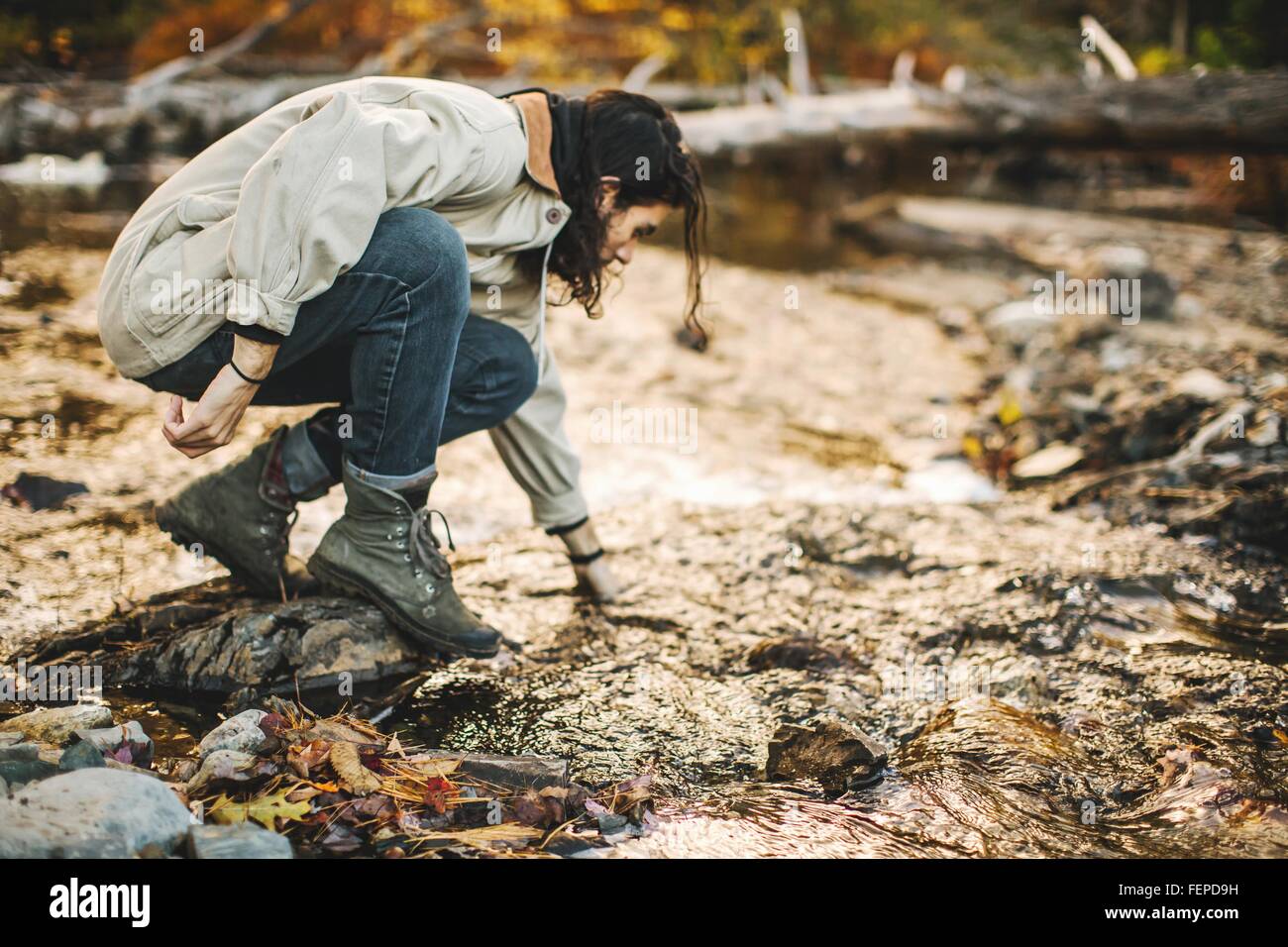 Young man, crouching down, exploring nature Stock Photo