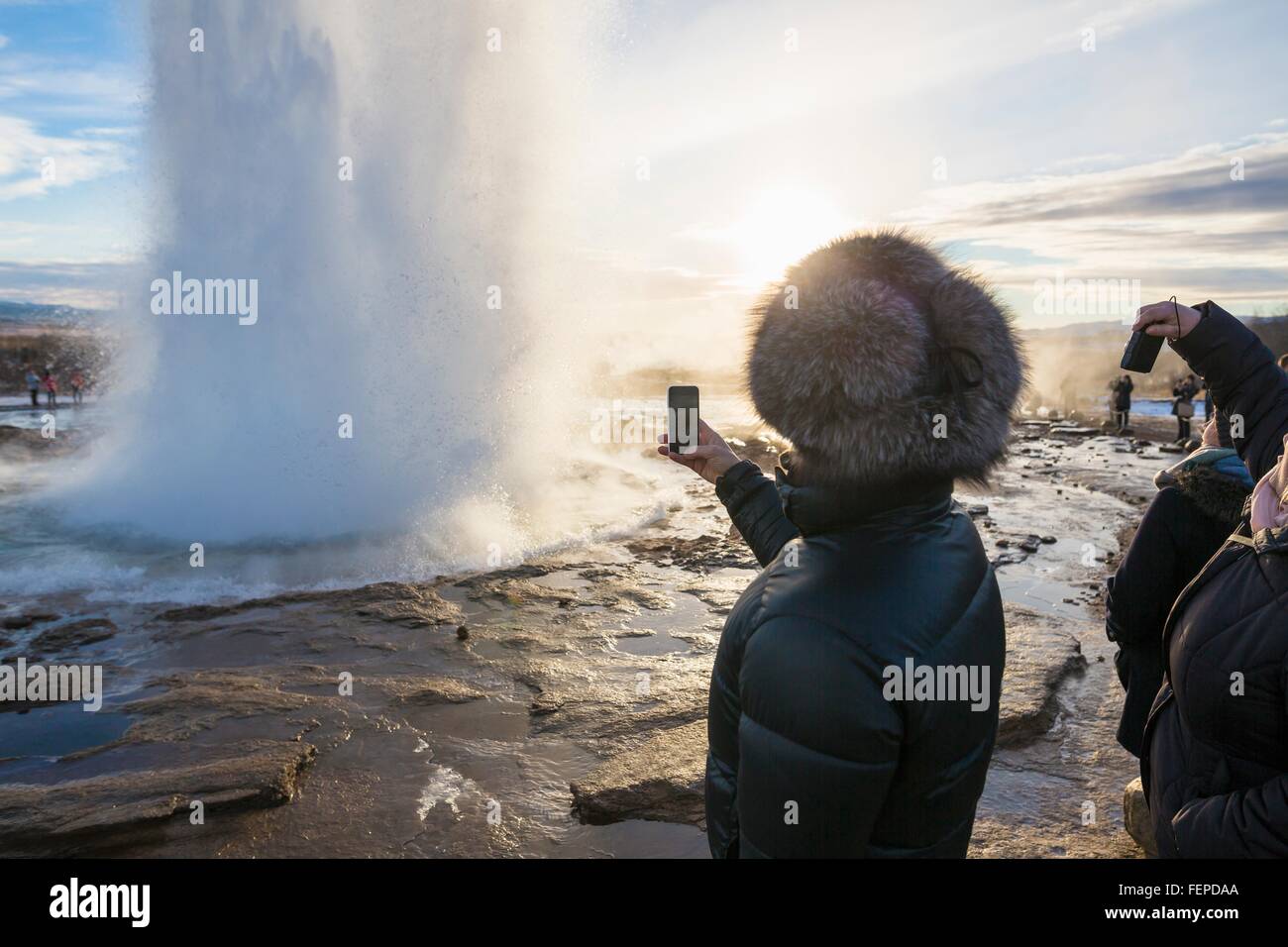 Woman photographing The Great Geysir, a geyser in the Haukadalur valley on the slopes of Laugarfjall hill, South West Iceland Stock Photo