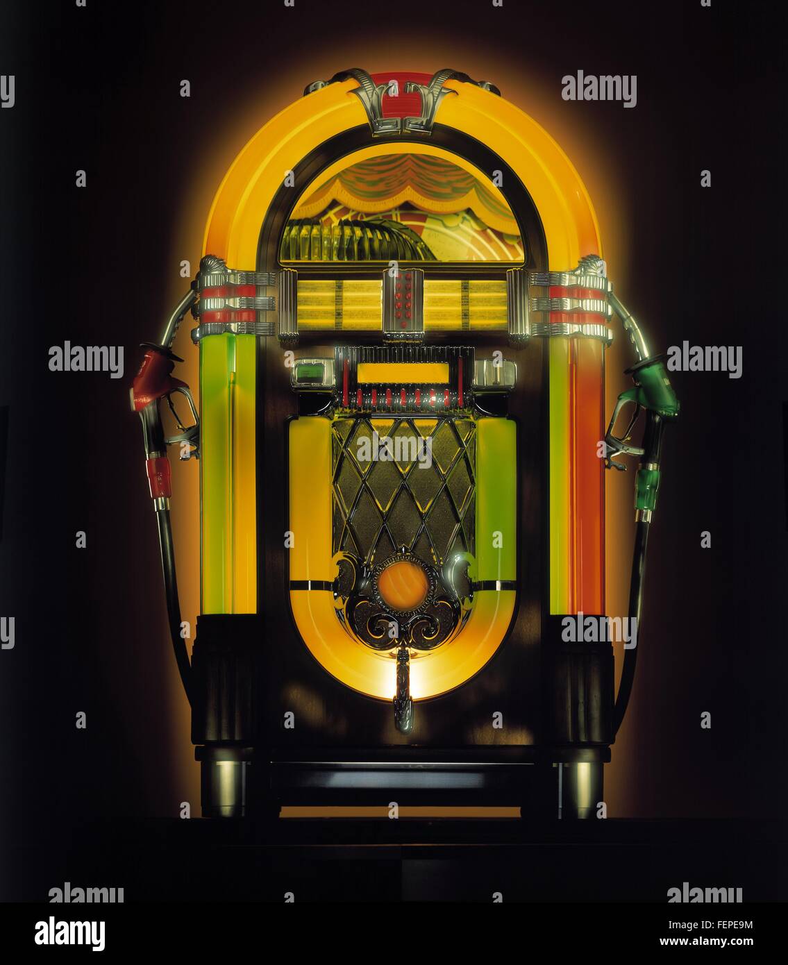Illuminated vintage jukebox with attached gas pump nozzles Stock Photo