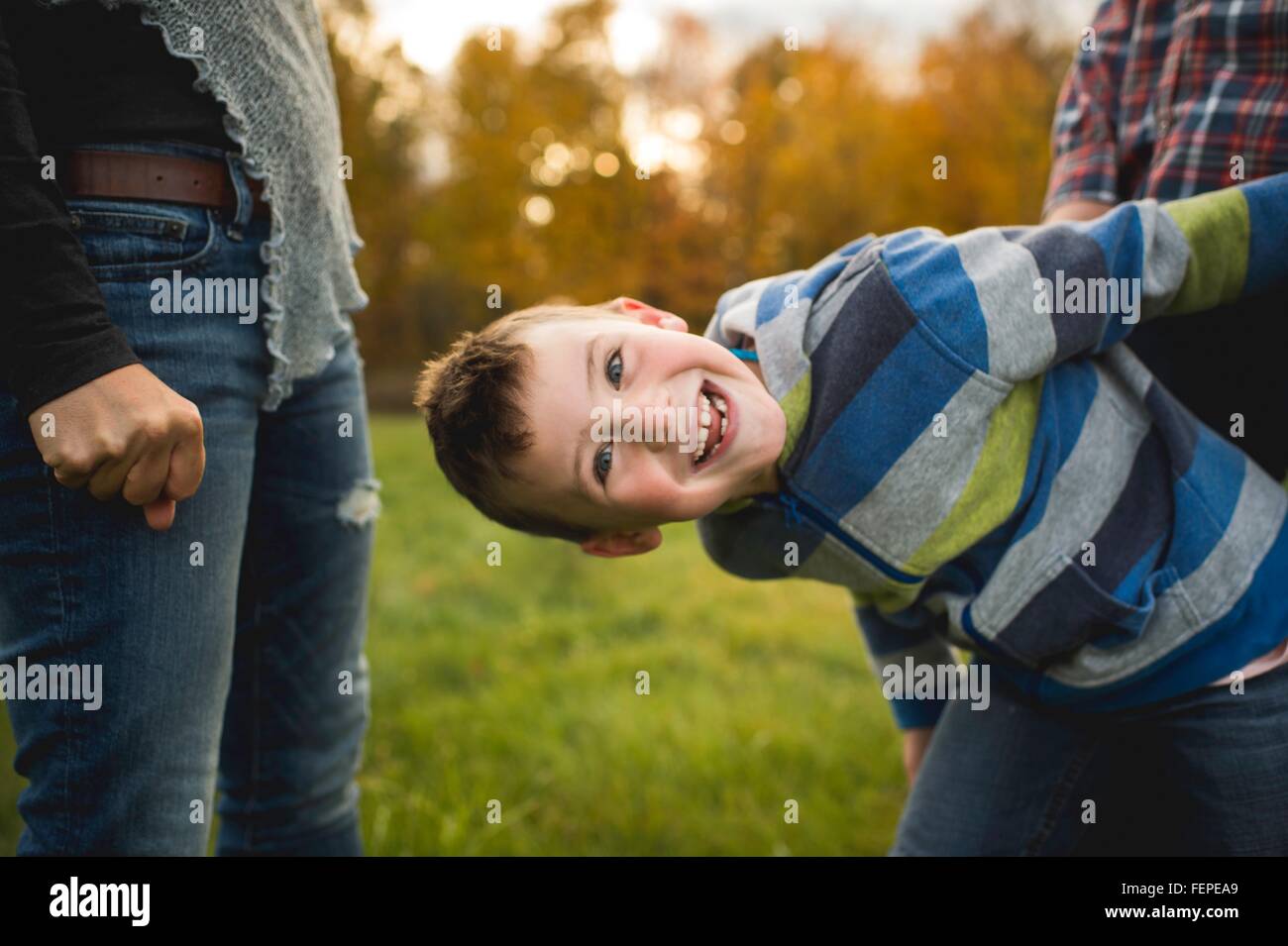 Boy with parents bending forwards looking at camera smiling Stock Photo