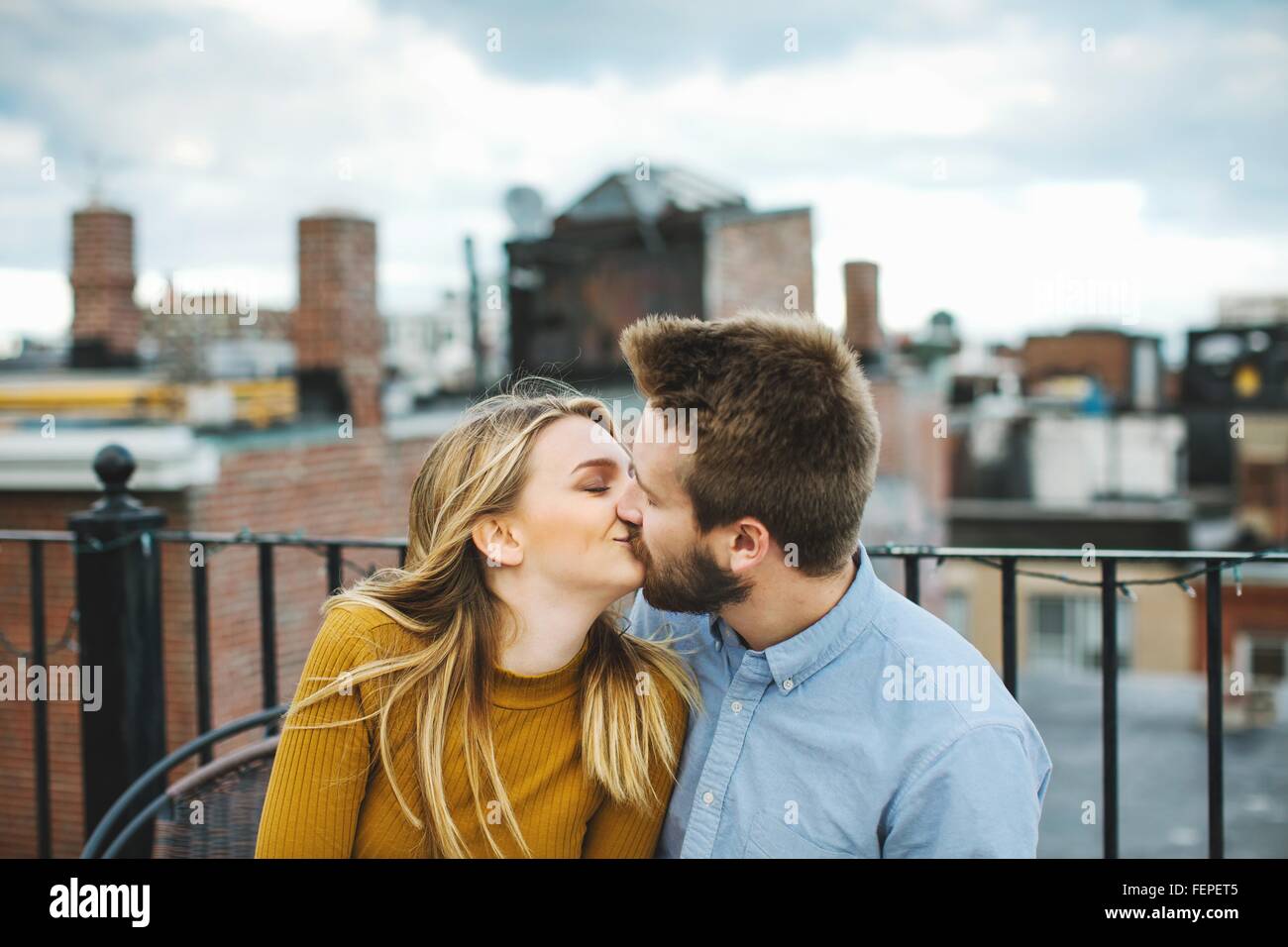 Romantic young couple kissing on city rooftop terrace Stock Photo