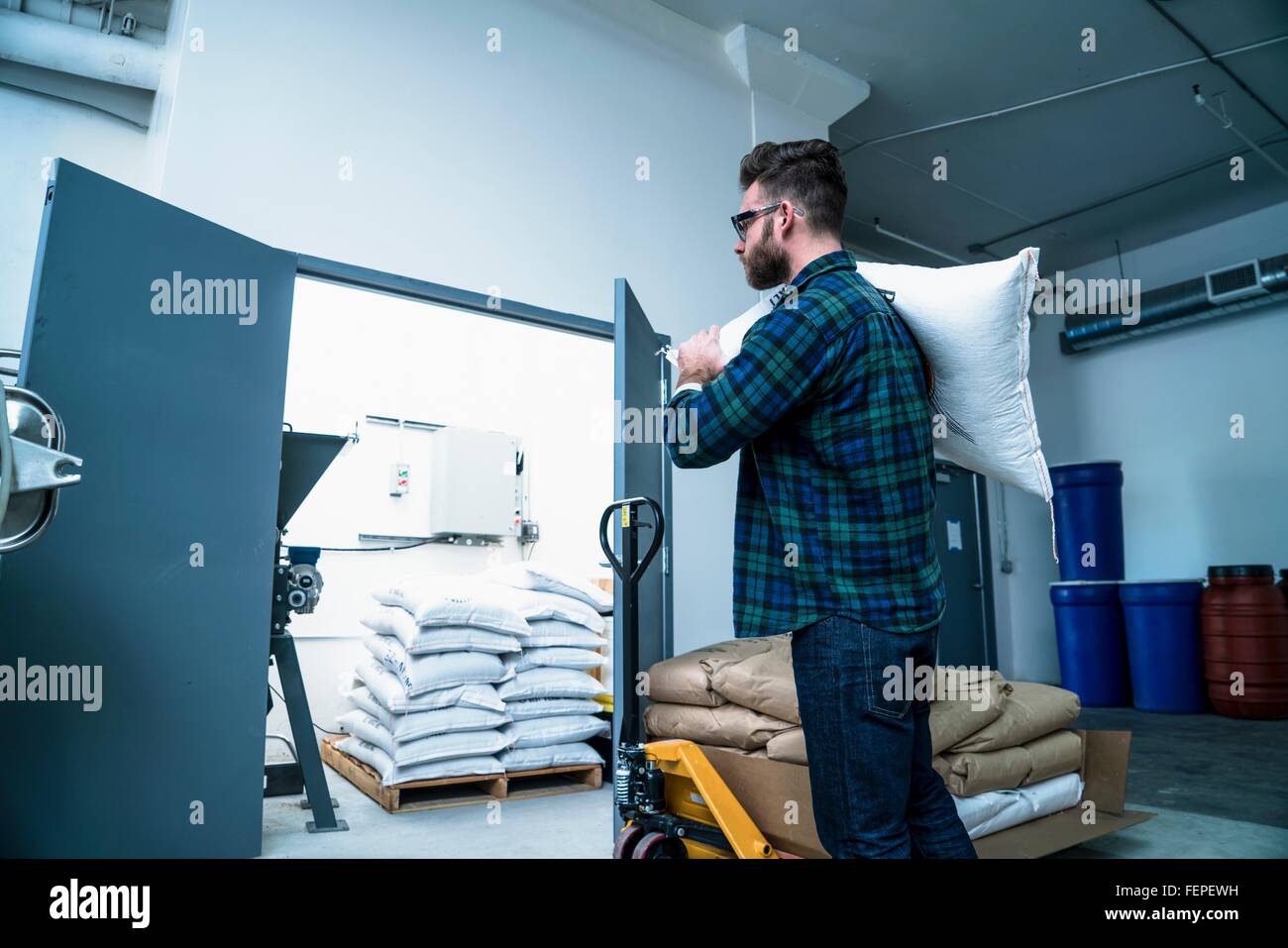 Side view of young man in warehouse carrying gunny sack on shoulder Stock Photo Alamy