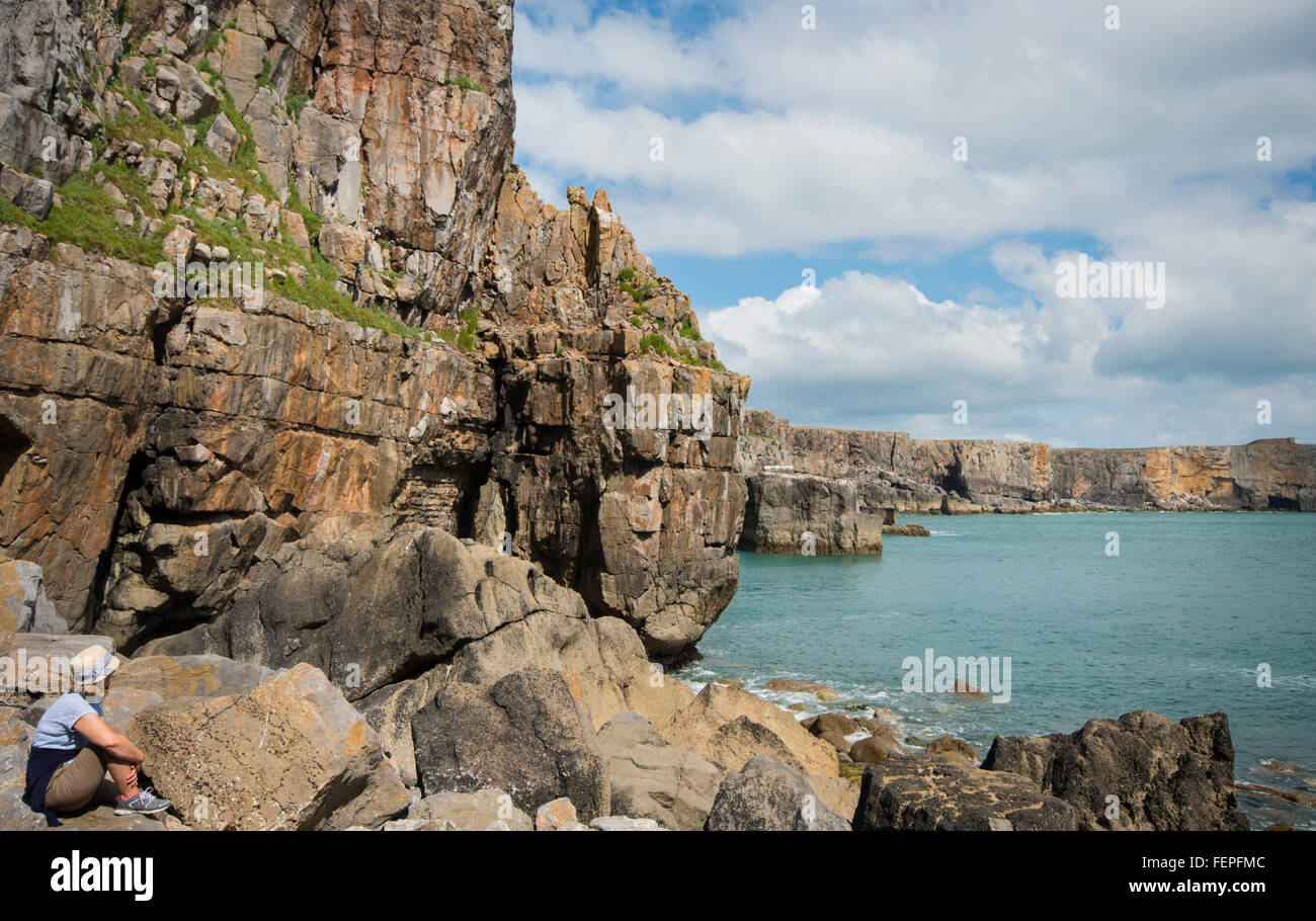 Female tourist admiring the dramatic cliffs along the Pembrokeshire coastline in South Wales Stock Photo