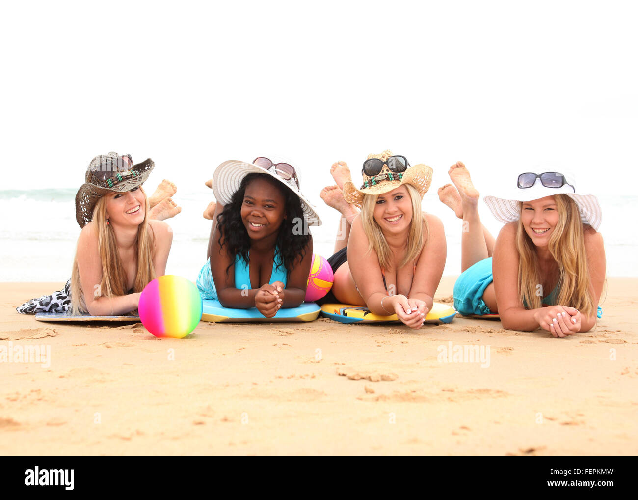 Four girls friends on the beach having fun under the summer sun ...