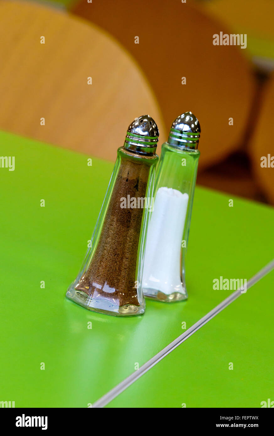 Glass condiment set containing salt and pepper on a green table in a cafe Stock Photo