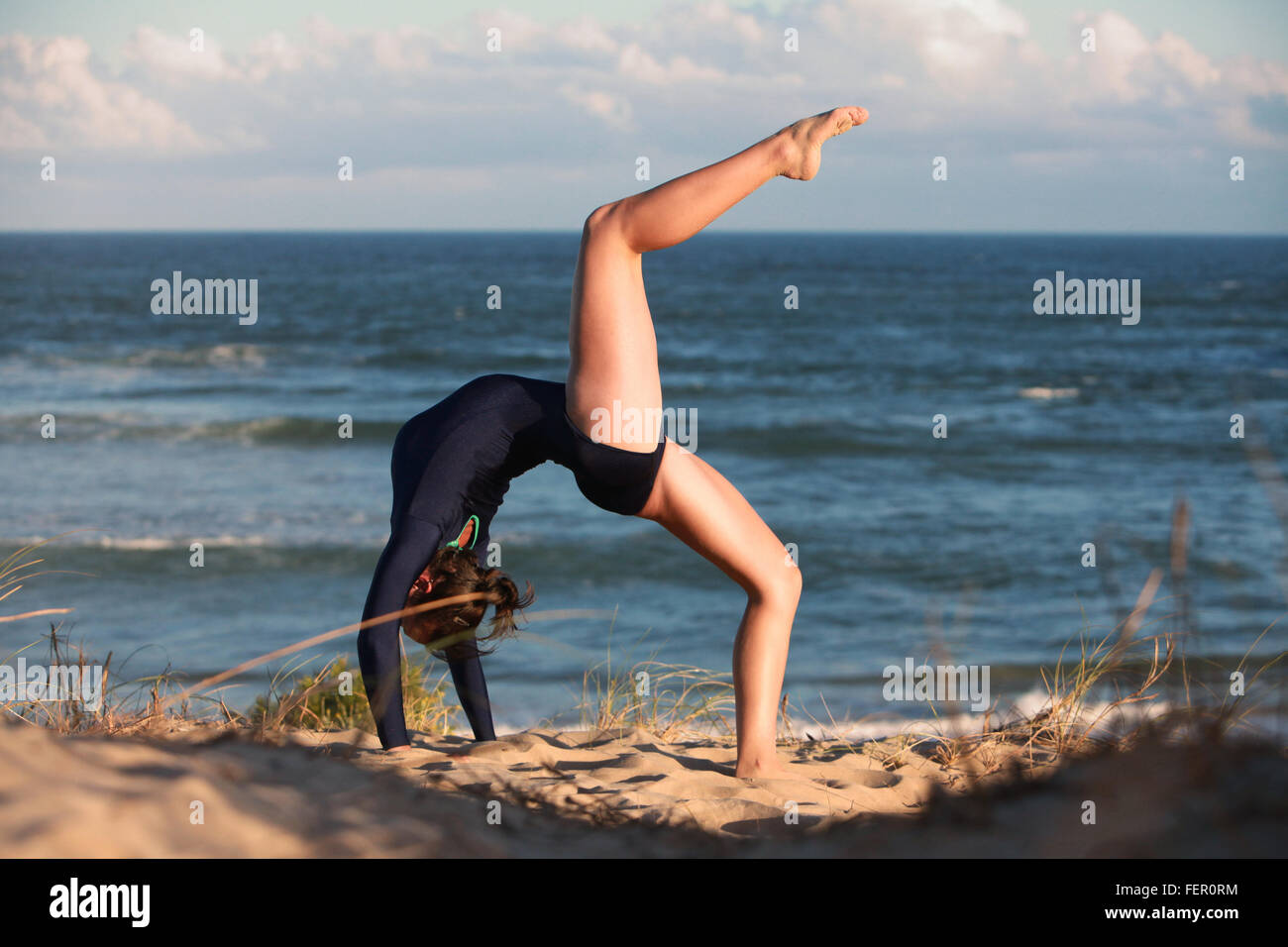 A gymnast is doing her routine on the beach in South Africa. Stock Photo