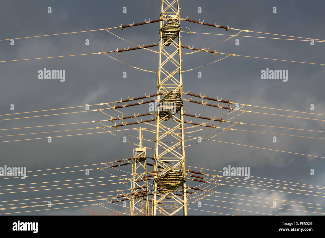 high-voltage electricity pylons against blue sky with rain clouds Stock Photo