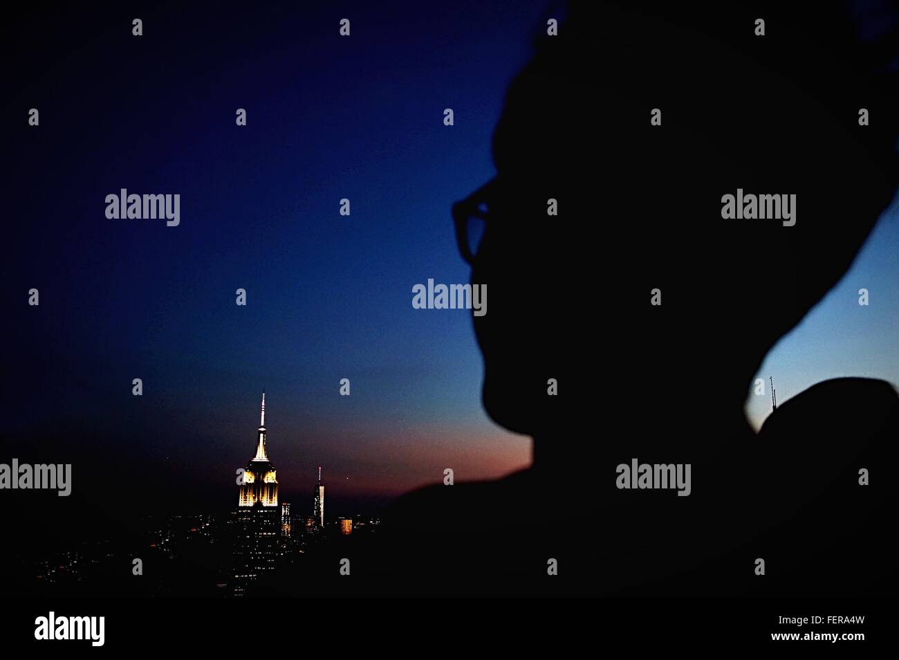 Close-Up Of Silhouette Person Standing On Rooftop Stock Photo