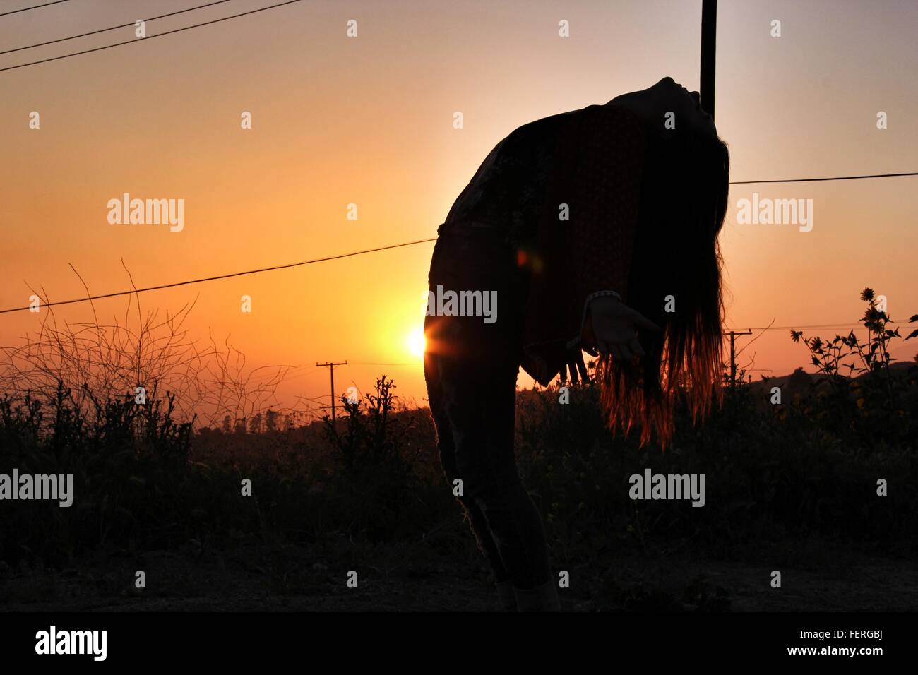 Silhouette Women Bending Backward On Field During Sunset Stock Photo