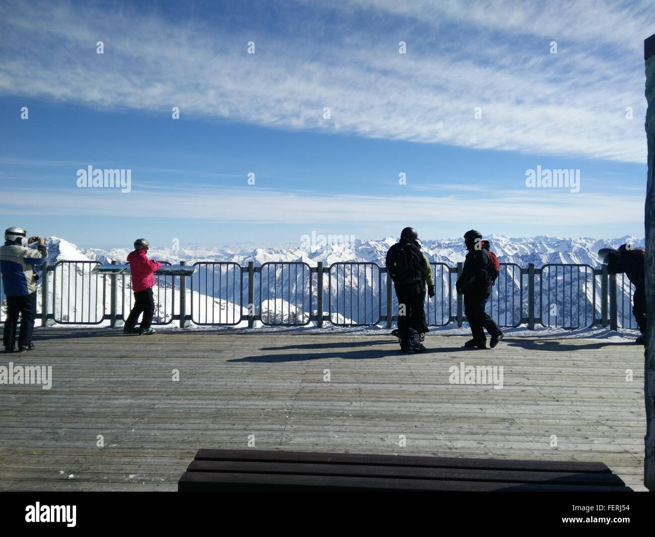 People On Observation Point Against Snowcapped Mountains Stock Photo