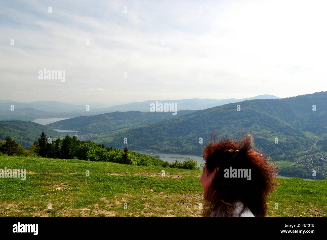 Woman With Curly Hair Looking Over Shoulder At Mountains Stock Photo