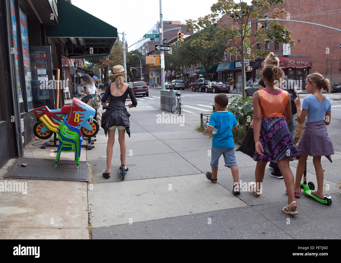 Children walk and use scooters on the sidewalk in Brooklyn, New York, USA. Stock Photo