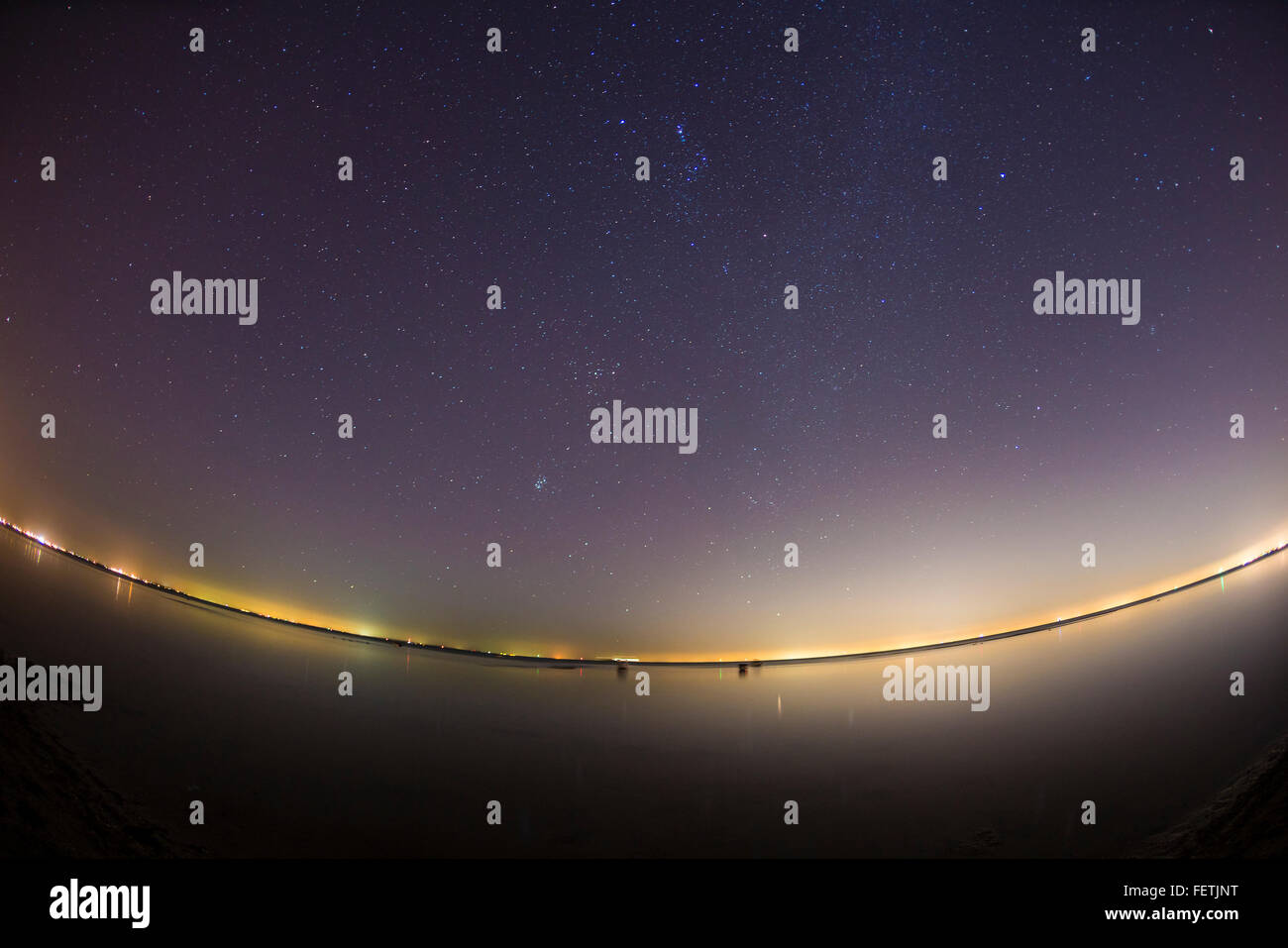 Starry night sky over clam water Stock Photo