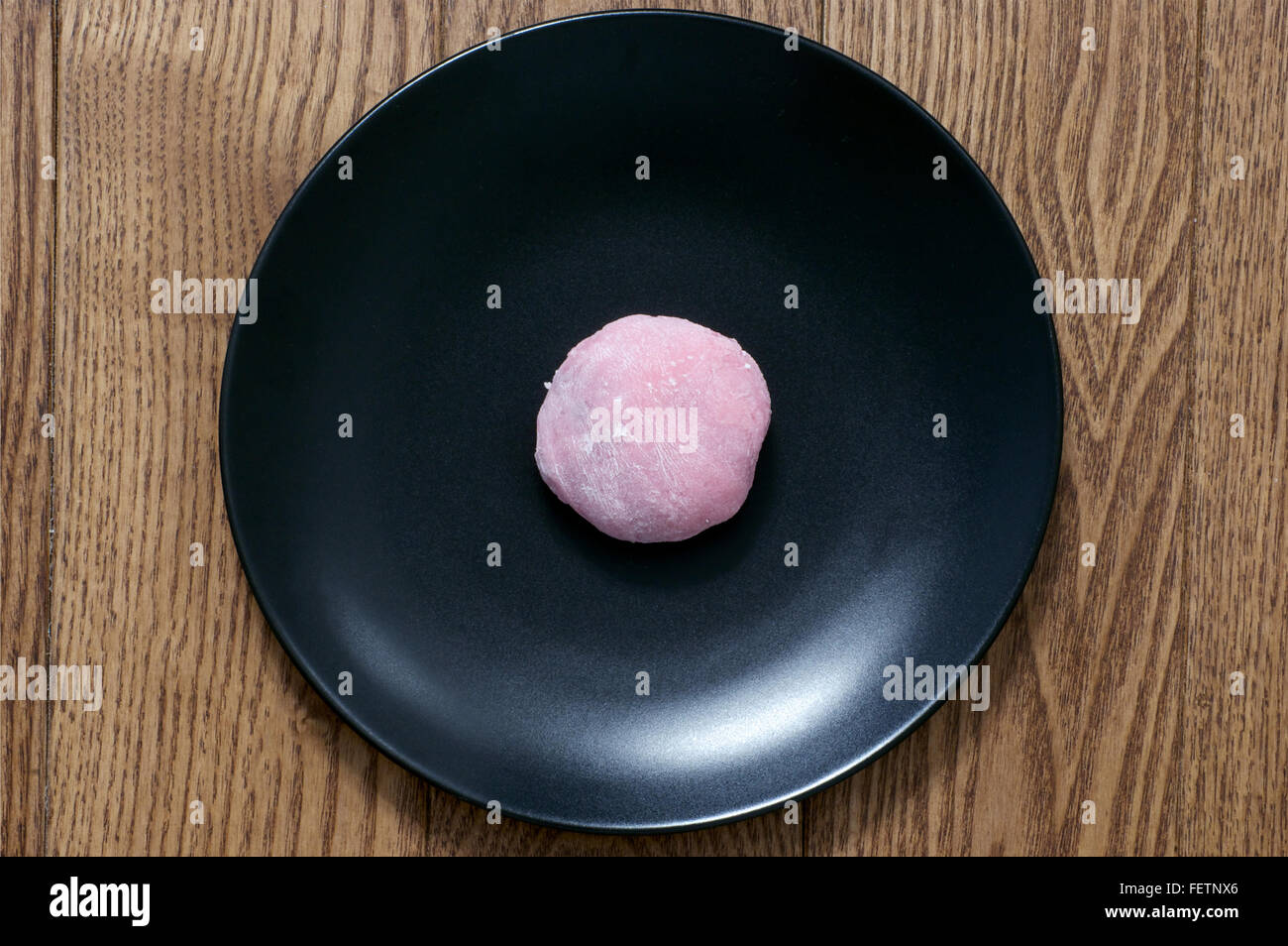 Pink mochi japanese sweet rice treat with filling on the black plate Stock Photo
