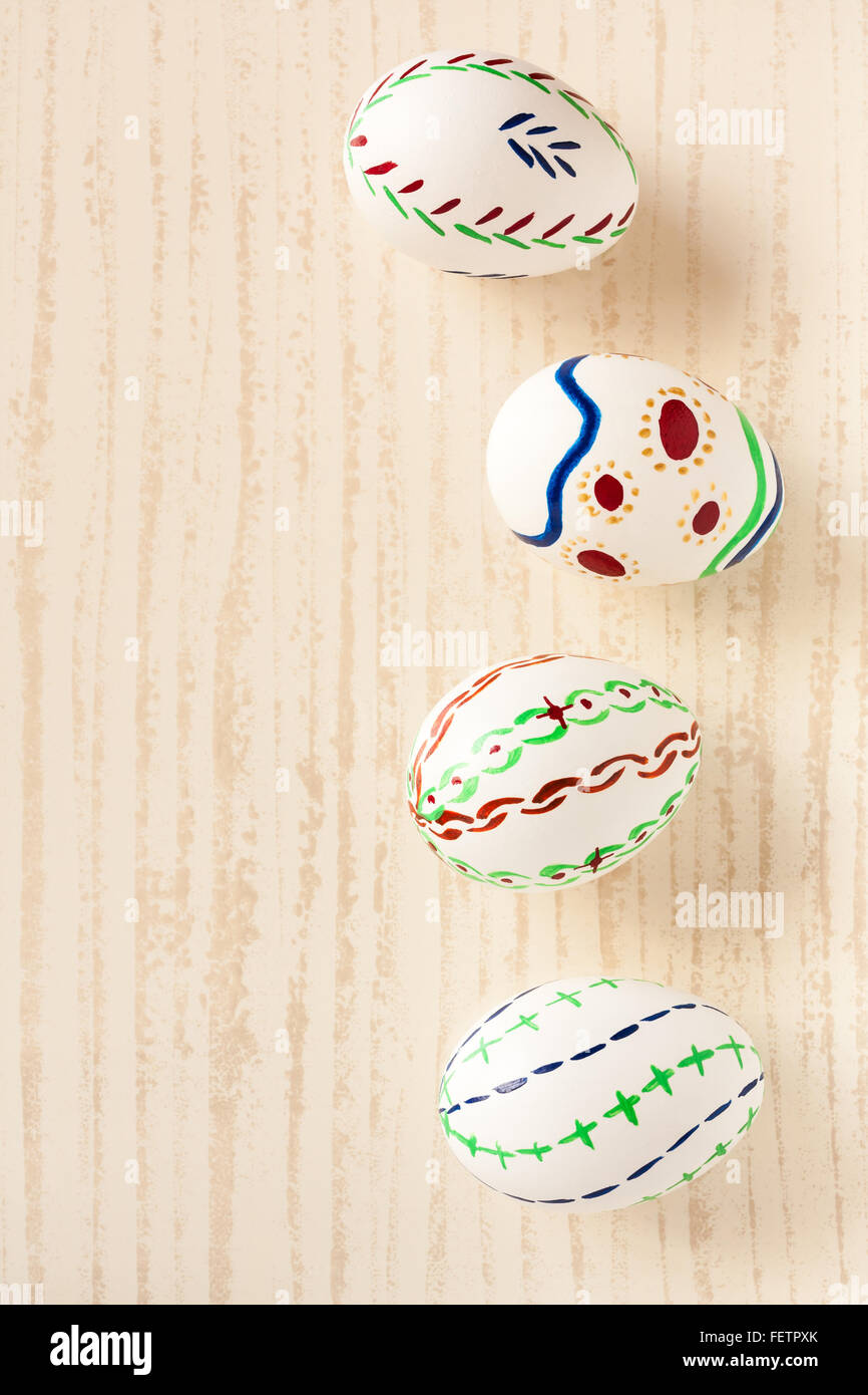 Natural white eggs with various patterns painted by hand for Easter and set on a tile. Festive background with natural light. Stock Photo