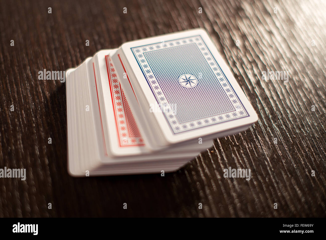 Deck of red and blue stacked playing cards on a wooden table with focus to the top card and copy space Stock Photo