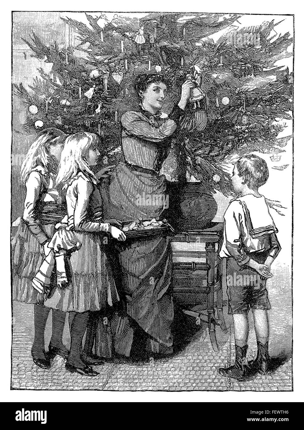 Black and white engraving of a Victorian family decorating a Christmas tree. Stock Photo
