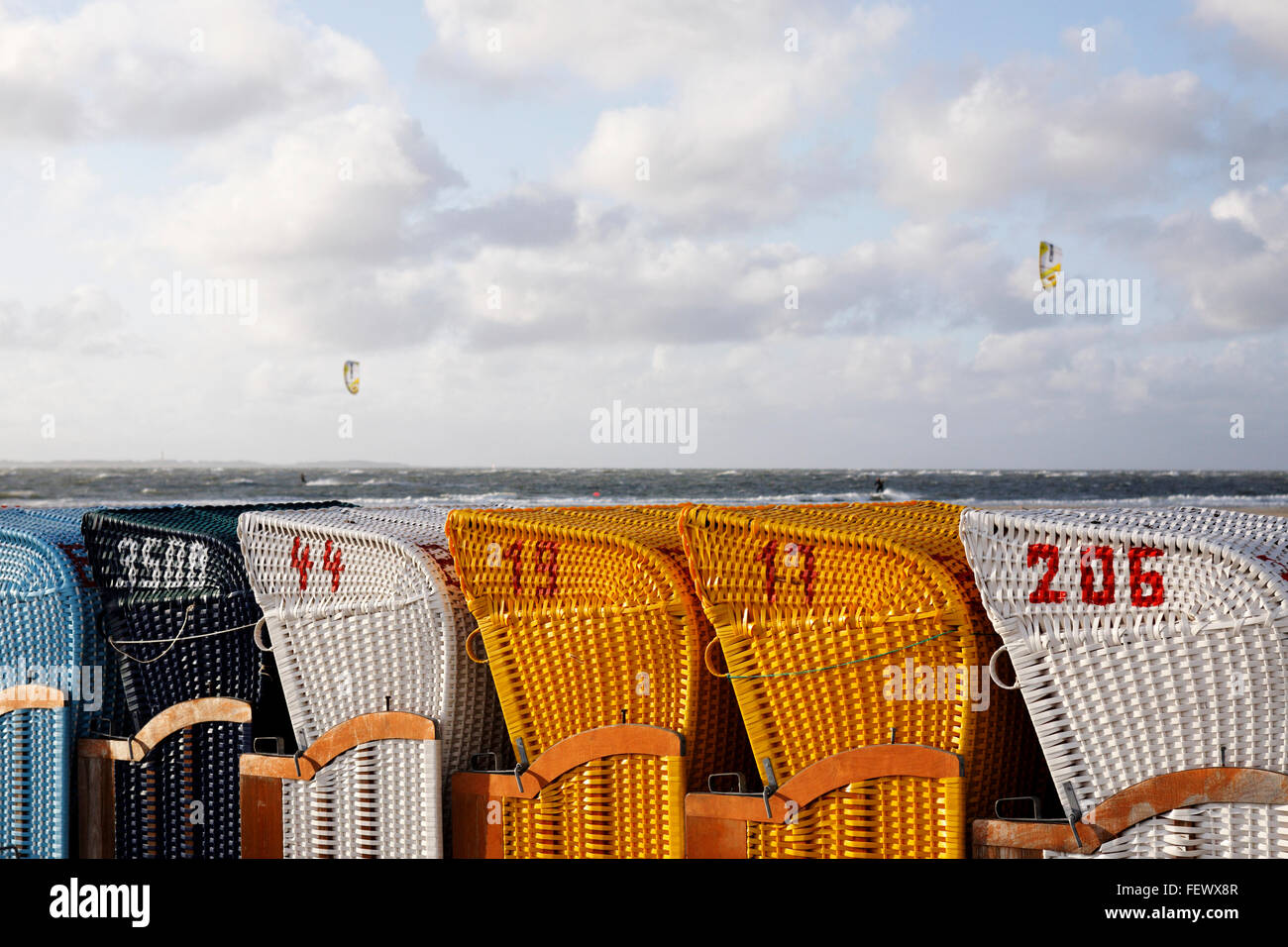 Strandkorb beach wind shelters with kite surfers, Amrum, Germany Stock Photo