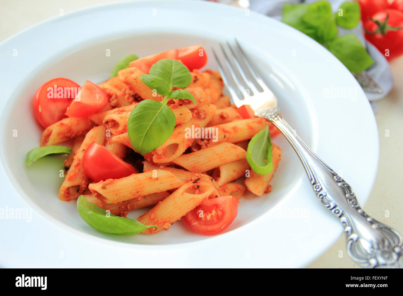 Penne pasta with tomato sauce and basil on white plate Stock Photo