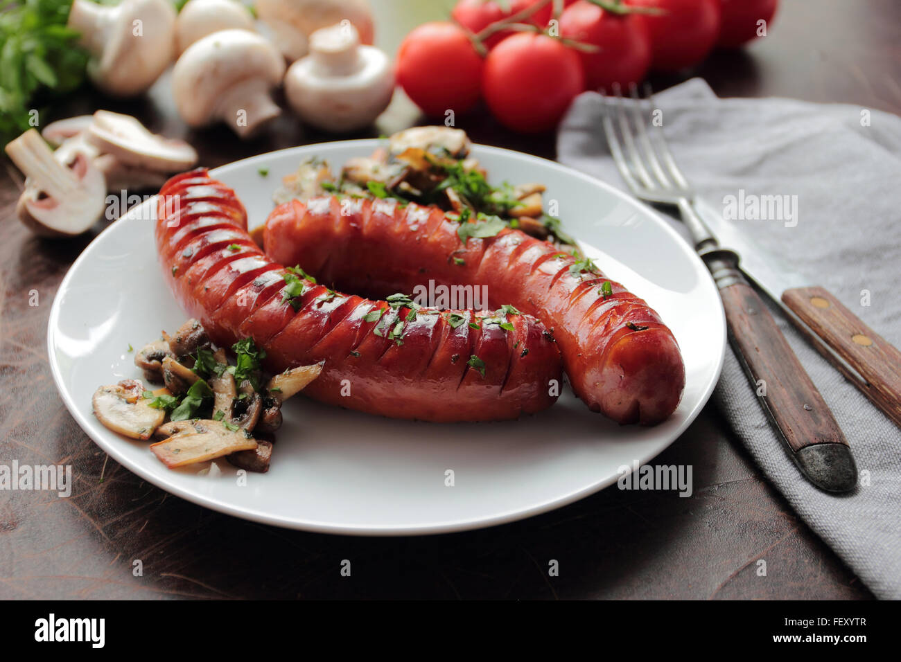 Grilled sausages with roasted mushrooms on white plate Stock Photo