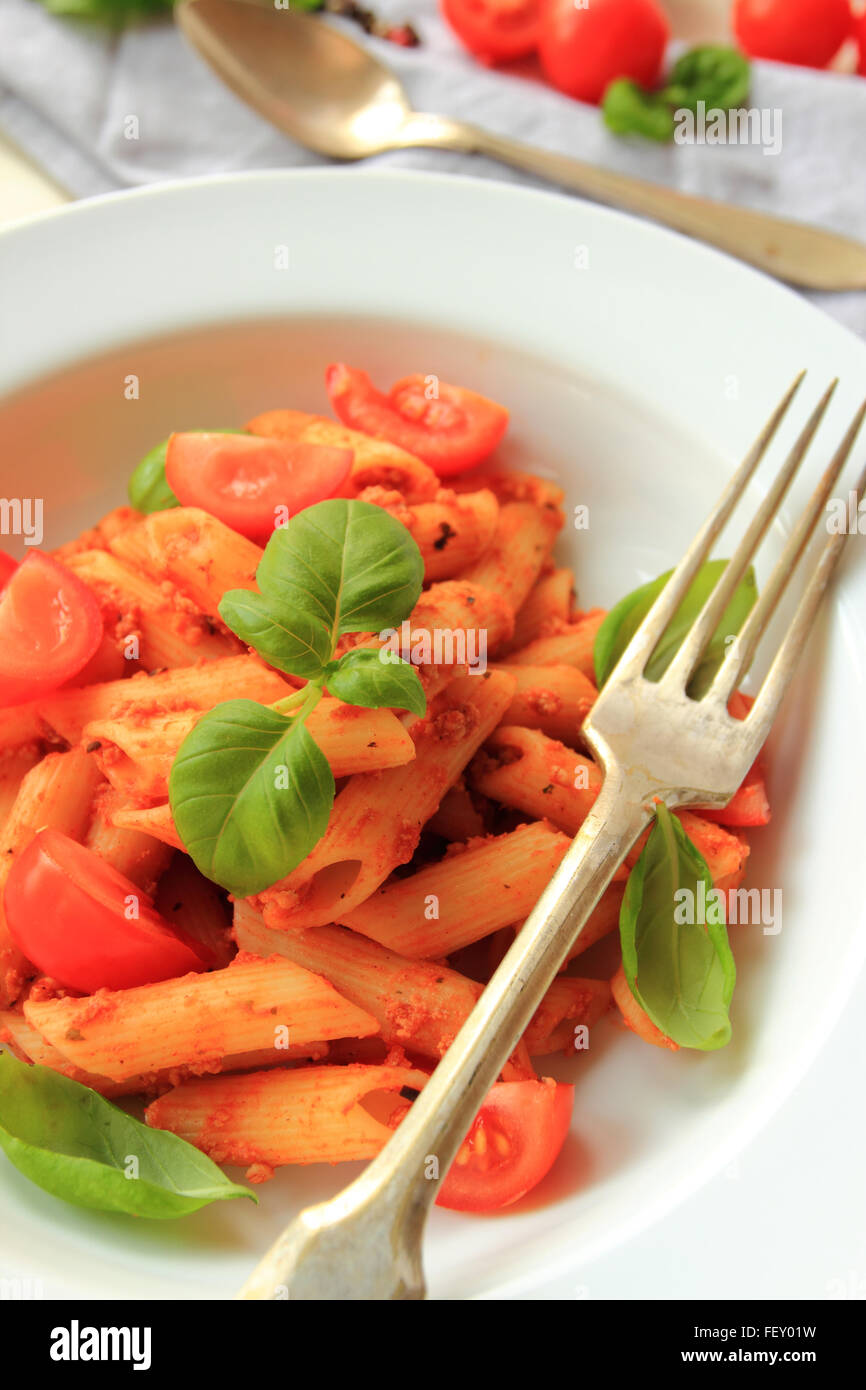 Penne pasta in tomato sauce with meat and fresh basil leafs Stock Photo