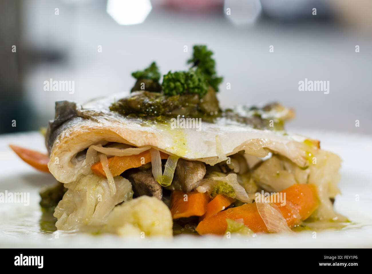 Sea bass with mixed seasonal vegetables on plate. Seabass fillet, mixed seasonal vegetables, lemon-herbs-caper butter Stock Photo