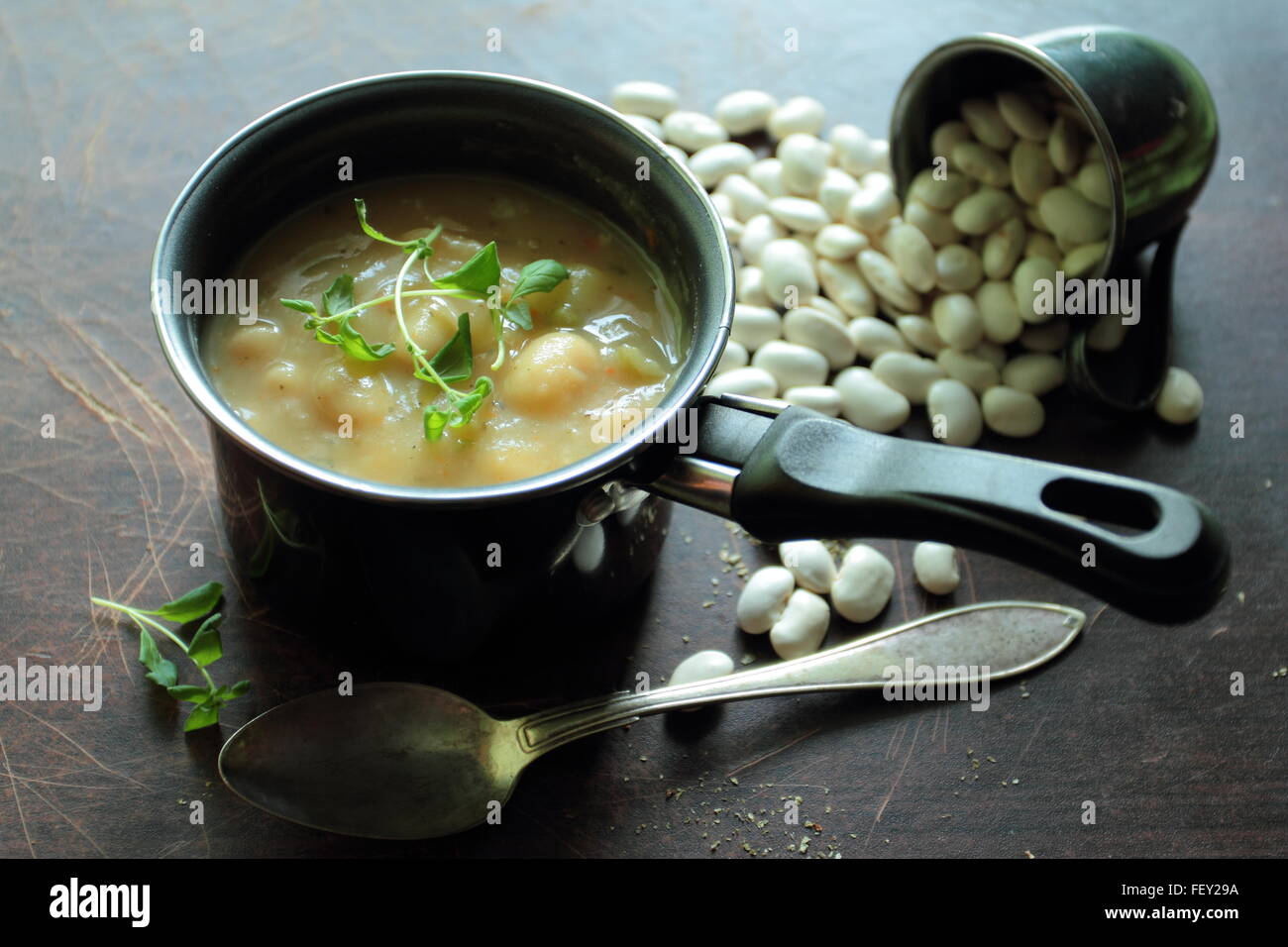 Little pot with bean soup with a spoon on a table Stock Photo