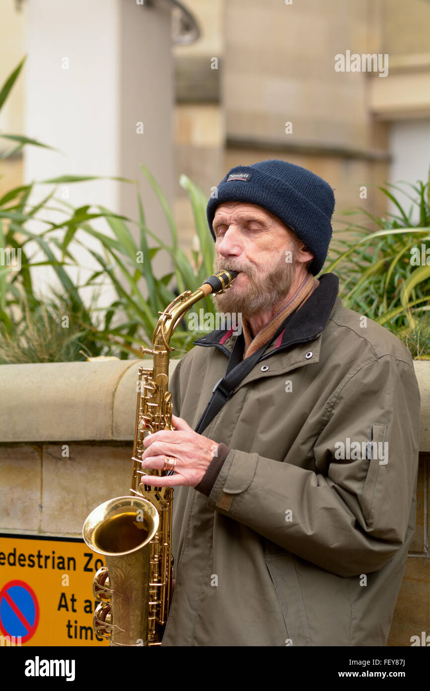 Busker playing saxophone in Bedford town centre in Bedfordshire, England Stock Photo