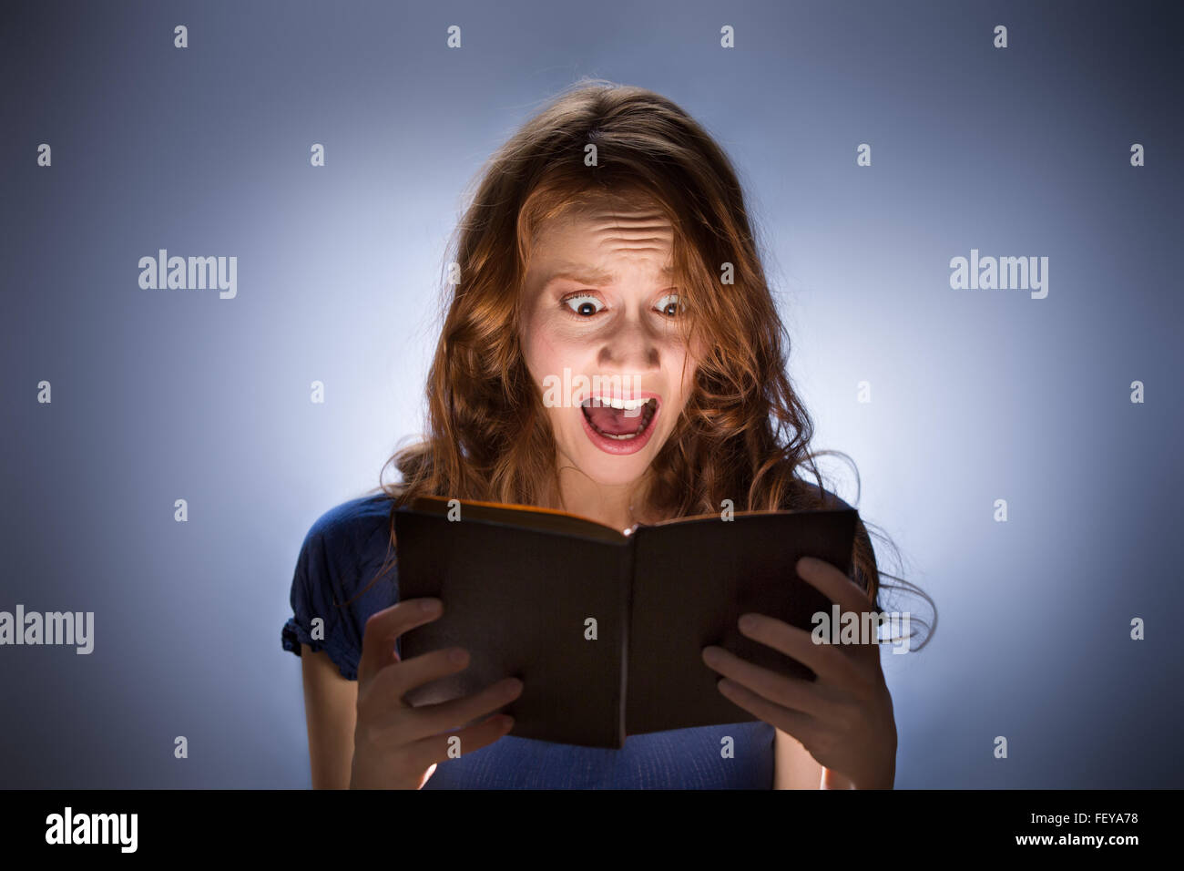 Concept shot of woman reading horror book and screaming Stock Photo