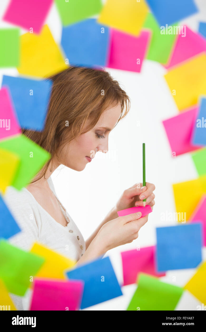 Beautiful woman writing note or idea, surrounded by lots of notes Stock Photo