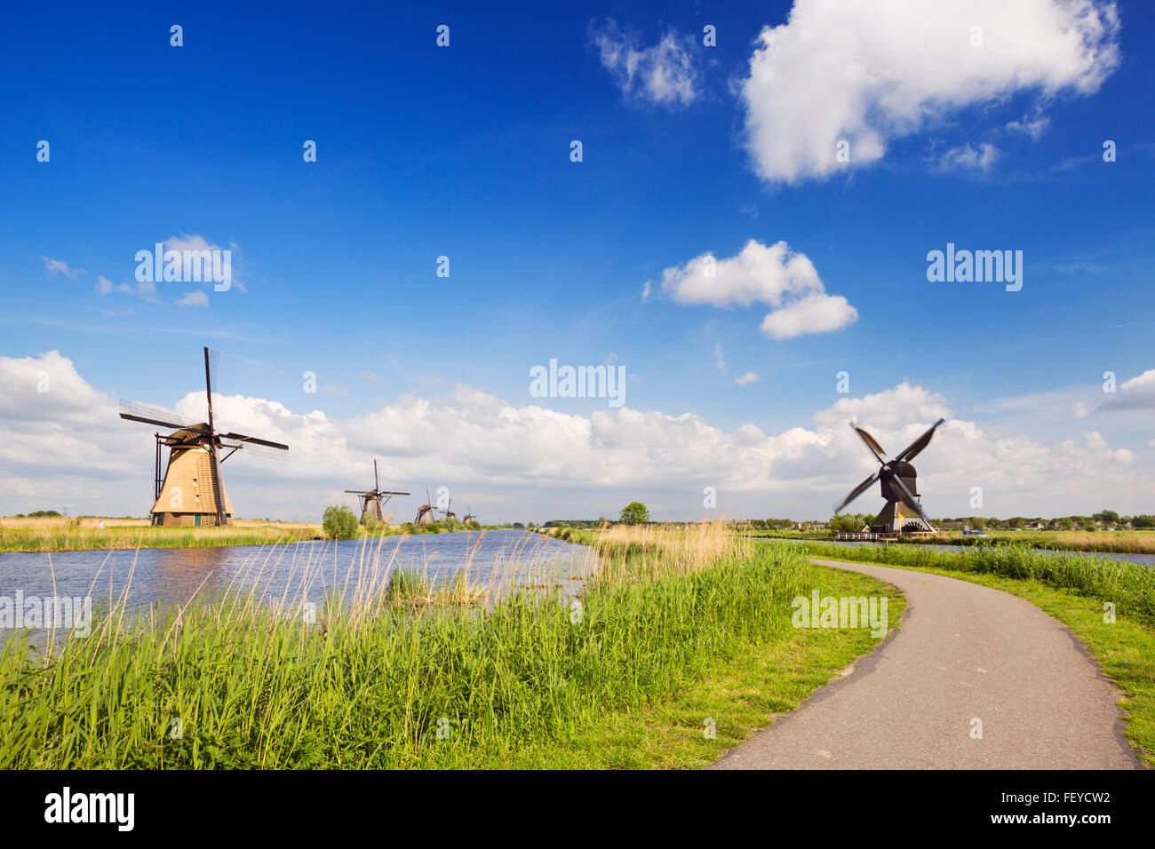 A path along traditional Dutch windmills on a bright and sunny day at the Kinderdijk in The Netherlands. Stock Photo