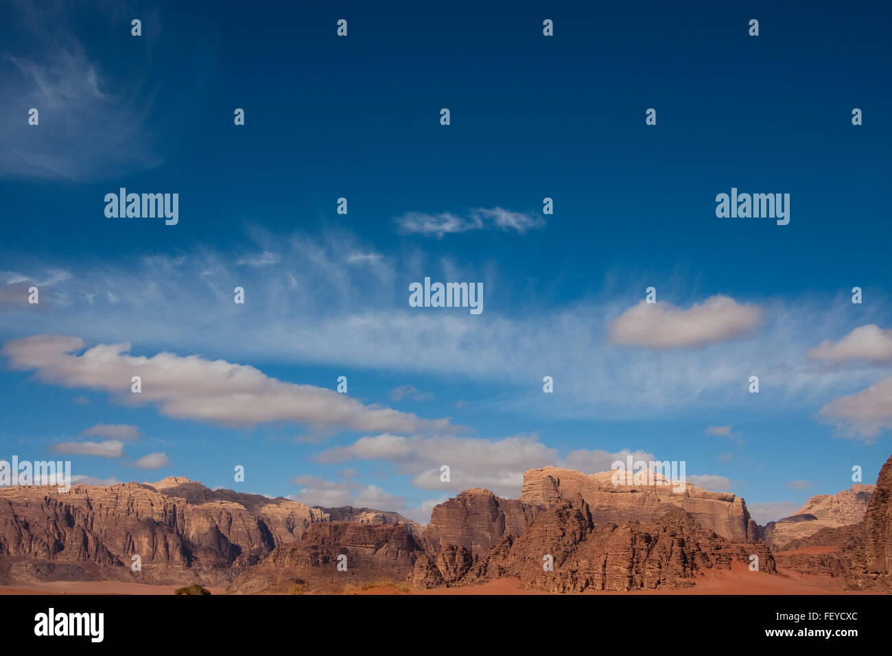 Mountains and sky with sparse clouds in Wadi Rum desert reservation, Jordan. Stock Photo