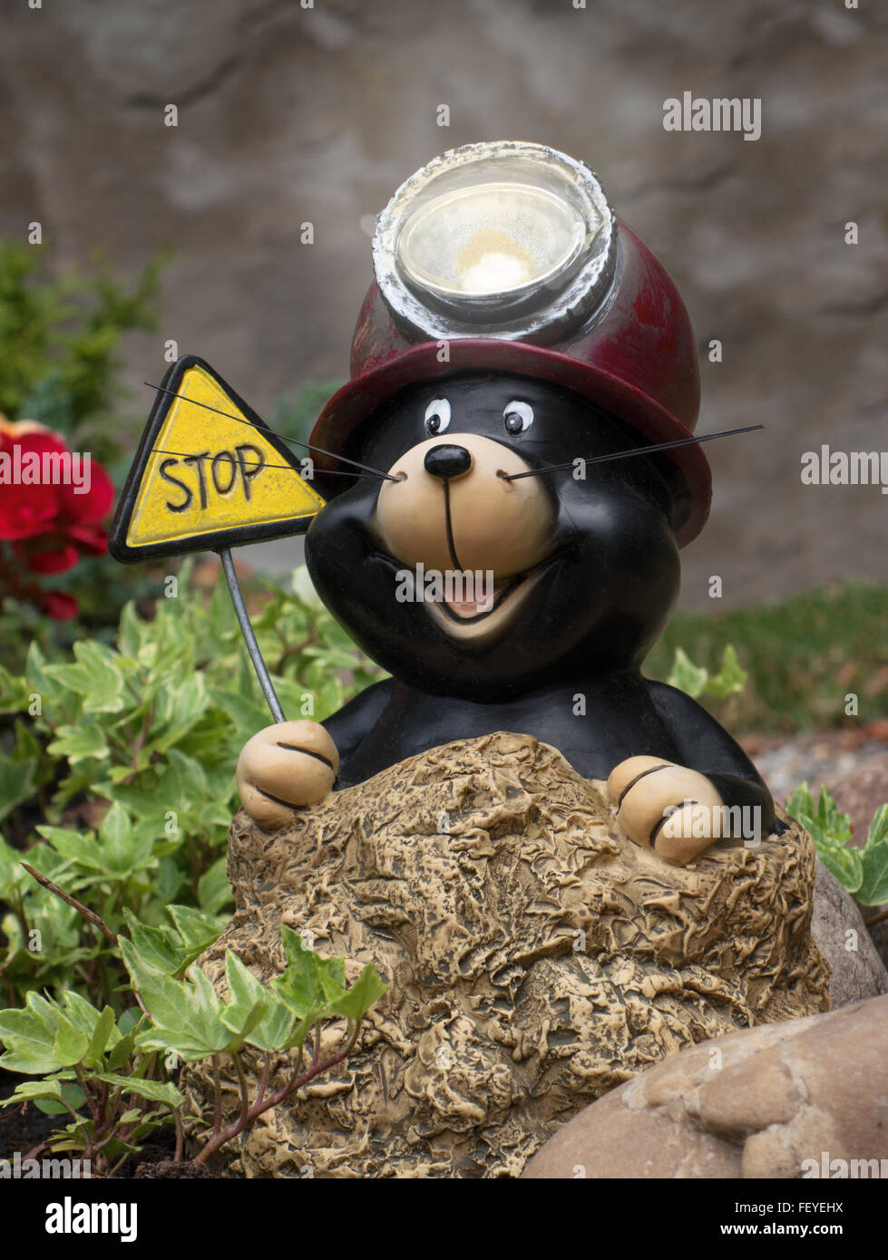 A funny, laughing mole figure with a helmet with miner's lamp and a sign STOP Stock Photo