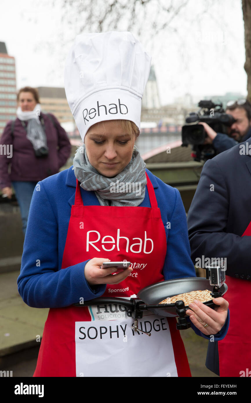 Westminster, London, UK. 9th February 2016. Sophy ridge, Sky news, uses her mobile phone with her go pro frying pan in the other hand  at the Rehab Parliamentary Pancake Race 2016 Credit:  Keith Larby/Alamy Live News Stock Photo