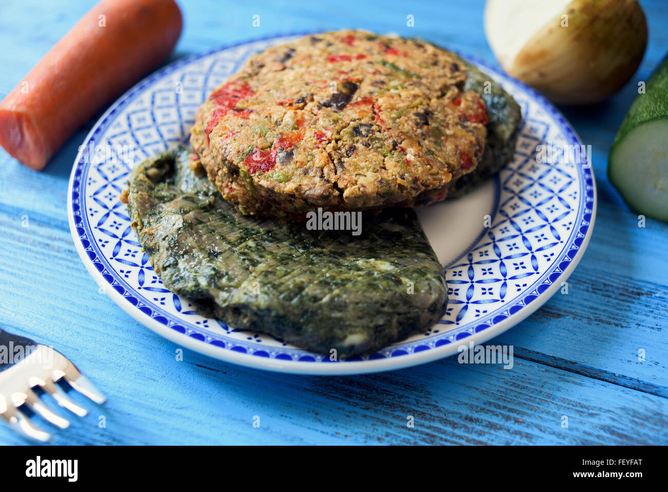 closeup of some different veggie burgers in a ceramic plate, on a rustic blue wooden table Stock Photo